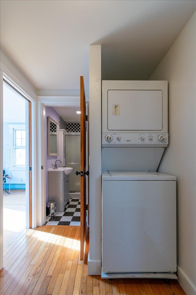 laundry room featuring light hardwood / wood-style floors, sink, and stacked washer / dryer