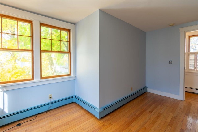 unfurnished room with a baseboard heating unit and light hardwood / wood-style flooring