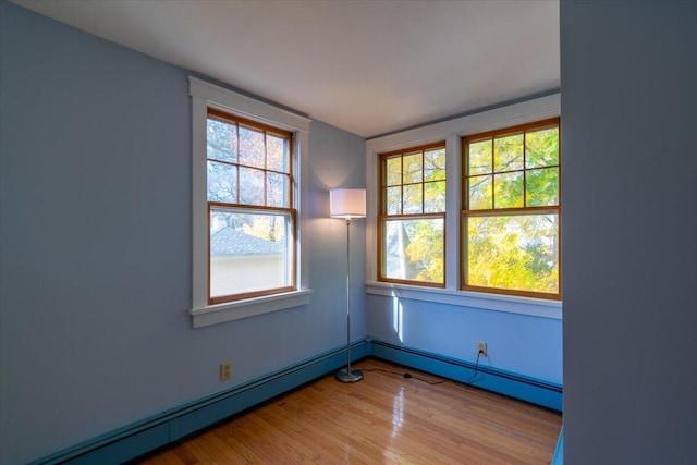 spare room featuring baseboard heating and light hardwood / wood-style floors