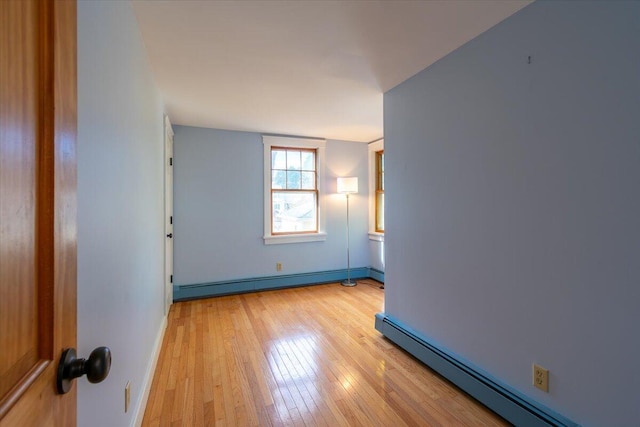 empty room featuring baseboard heating and light hardwood / wood-style flooring