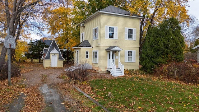 view of front of house featuring a front lawn and a storage unit