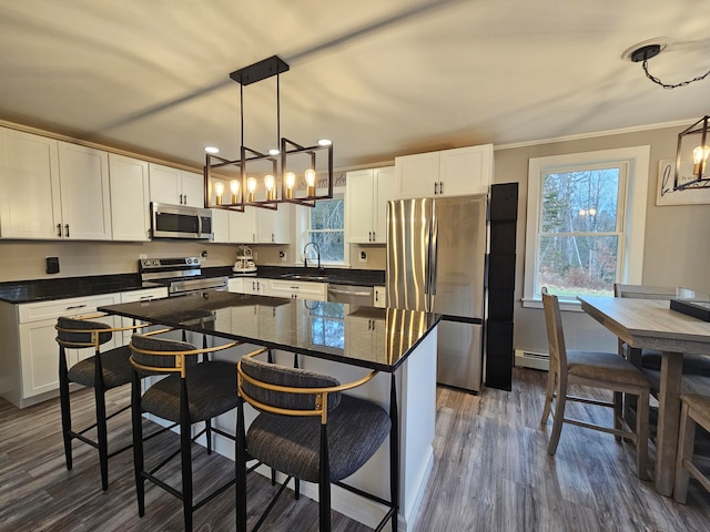 kitchen with a center island, dark hardwood / wood-style flooring, hanging light fixtures, and appliances with stainless steel finishes