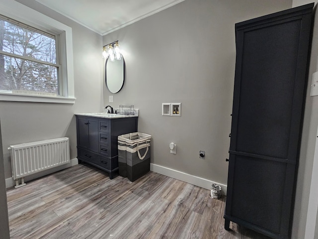 bathroom with hardwood / wood-style floors, vanity, radiator, and ornamental molding