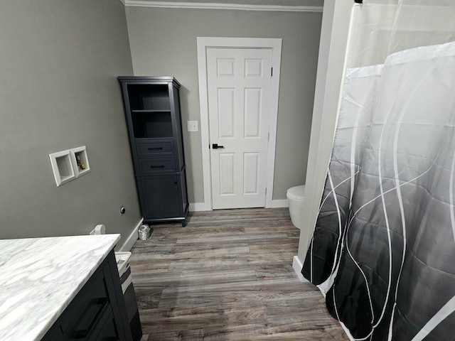 bathroom featuring walk in shower, toilet, hardwood / wood-style flooring, vanity, and ornamental molding