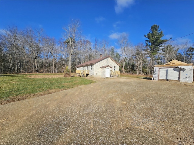 view of property exterior featuring a lawn, a garage, and an outbuilding