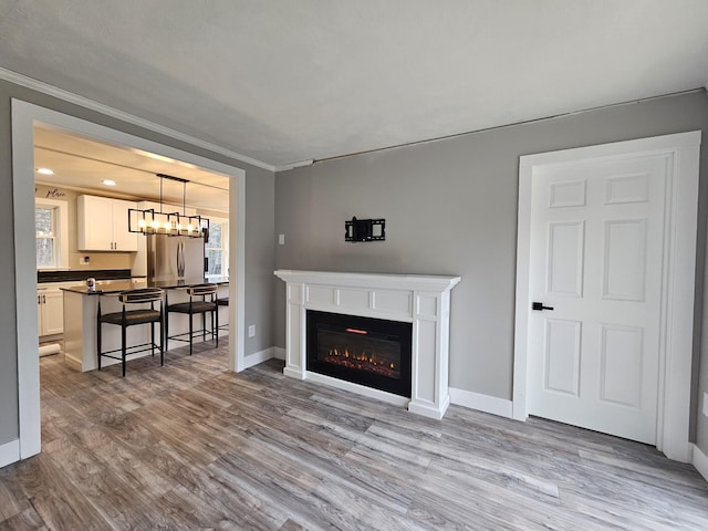 living room featuring an inviting chandelier, ornamental molding, and light hardwood / wood-style flooring