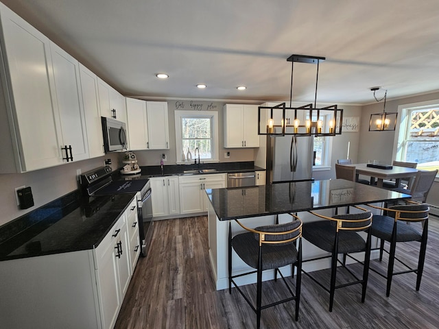 kitchen featuring pendant lighting, sink, dark hardwood / wood-style floors, appliances with stainless steel finishes, and white cabinetry