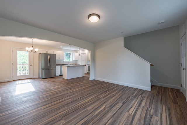 unfurnished living room with sink, a chandelier, and dark hardwood / wood-style floors