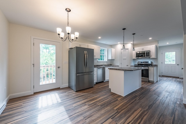 kitchen with a center island, hanging light fixtures, dark hardwood / wood-style flooring, white cabinetry, and stainless steel appliances