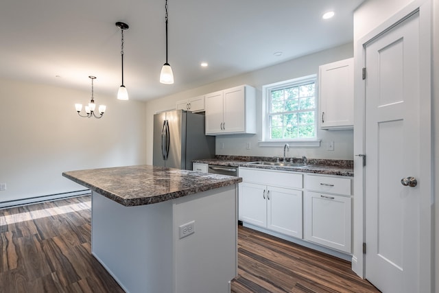 kitchen featuring appliances with stainless steel finishes, sink, a center island, white cabinetry, and hanging light fixtures