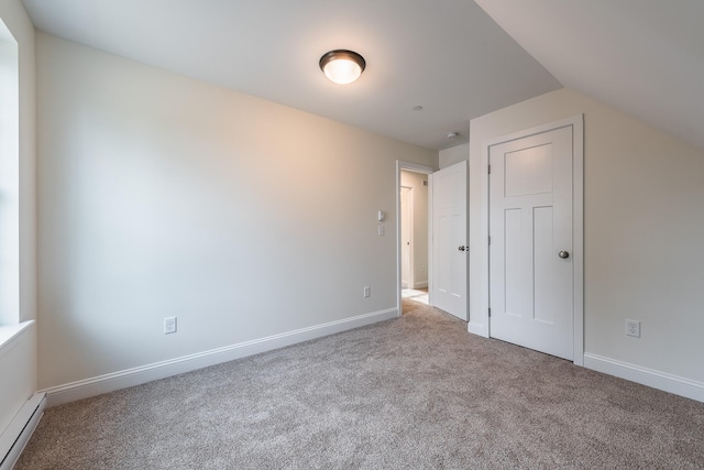 interior space featuring light colored carpet, lofted ceiling, and a baseboard radiator