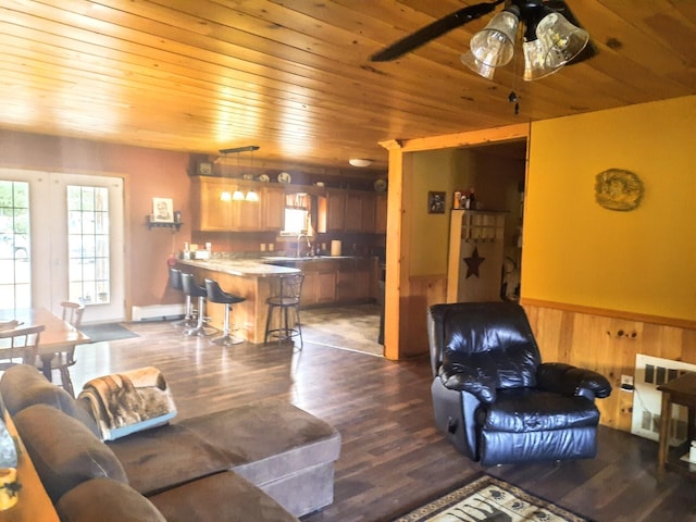 living room featuring wood walls, dark wood-type flooring, ceiling fan, and wooden ceiling