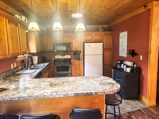 kitchen with white fridge, stainless steel stove, dark hardwood / wood-style flooring, a breakfast bar, and kitchen peninsula