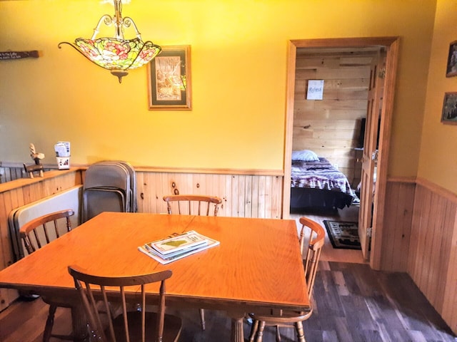 dining space featuring wooden walls and dark hardwood / wood-style flooring
