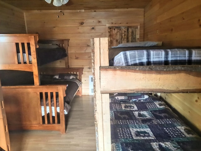 bedroom with wood-type flooring and wooden walls