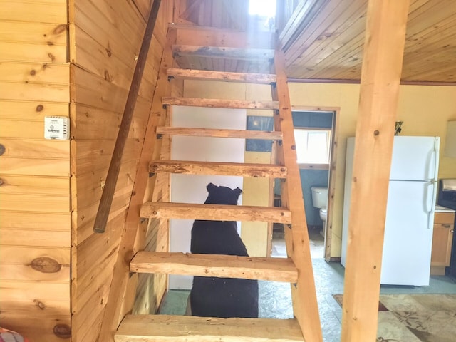 staircase featuring wooden walls