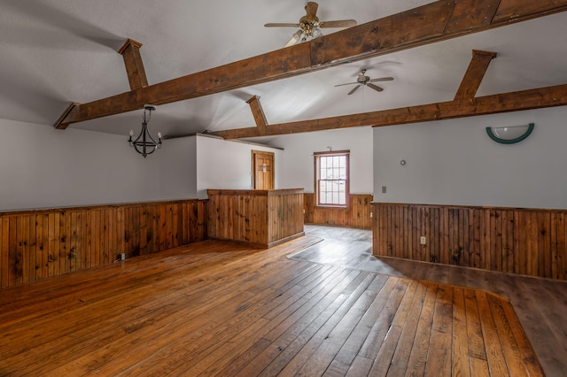 empty room with lofted ceiling with beams, light hardwood / wood-style flooring, and ceiling fan with notable chandelier