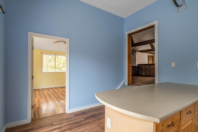 kitchen featuring beamed ceiling, wood-type flooring, and light brown cabinetry