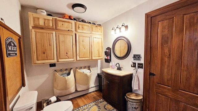 bathroom featuring vanity, wood-type flooring, a baseboard radiator, and toilet