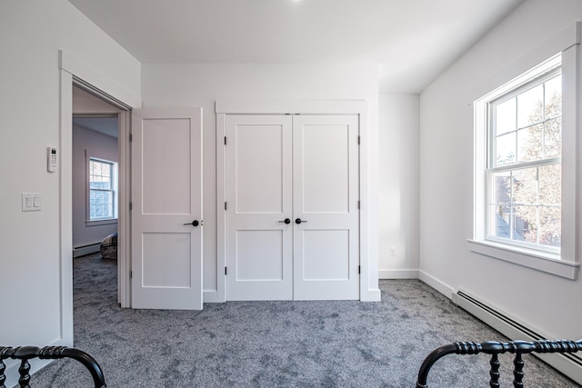 unfurnished bedroom featuring a baseboard heating unit, light colored carpet, and multiple windows