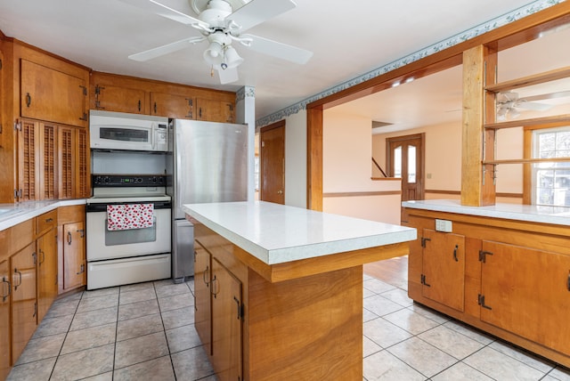 kitchen featuring ceiling fan, a kitchen island, white appliances, and light tile patterned floors