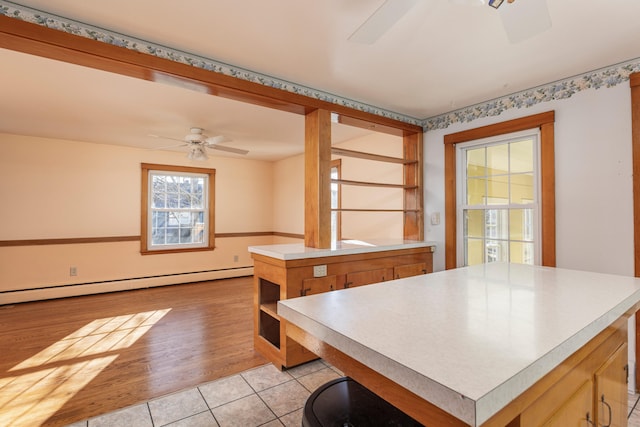 kitchen with ceiling fan, a kitchen island, light hardwood / wood-style floors, and a baseboard radiator