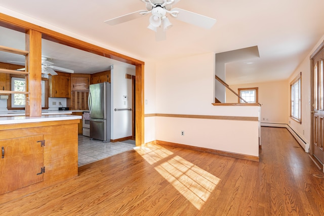 kitchen with stainless steel refrigerator, ceiling fan, and light hardwood / wood-style floors