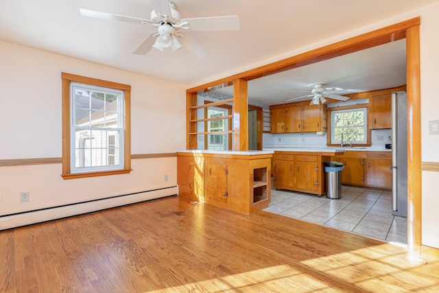 kitchen featuring light hardwood / wood-style floors, a baseboard radiator, stainless steel refrigerator, and a healthy amount of sunlight