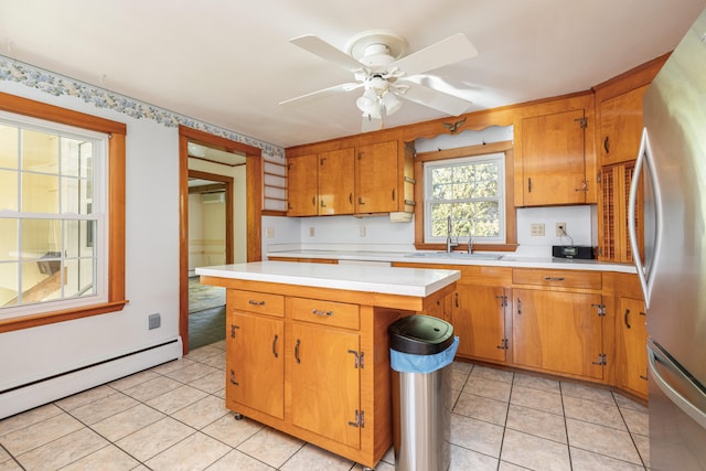 kitchen with sink, ceiling fan, light tile patterned floors, a baseboard radiator, and stainless steel refrigerator