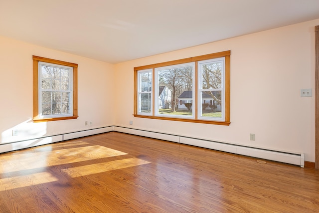 unfurnished room featuring hardwood / wood-style flooring, a healthy amount of sunlight, and a baseboard radiator