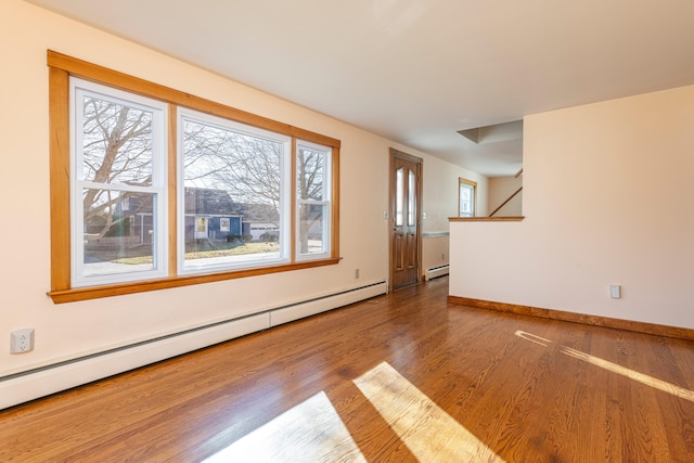 unfurnished room featuring hardwood / wood-style floors, a baseboard radiator, and a healthy amount of sunlight