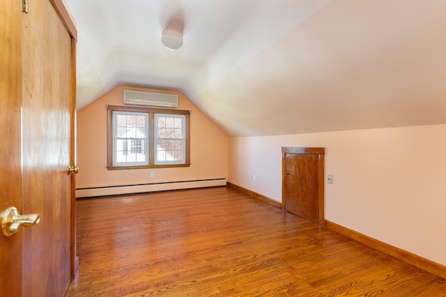 additional living space featuring wood-type flooring, a wall unit AC, baseboard heating, and lofted ceiling