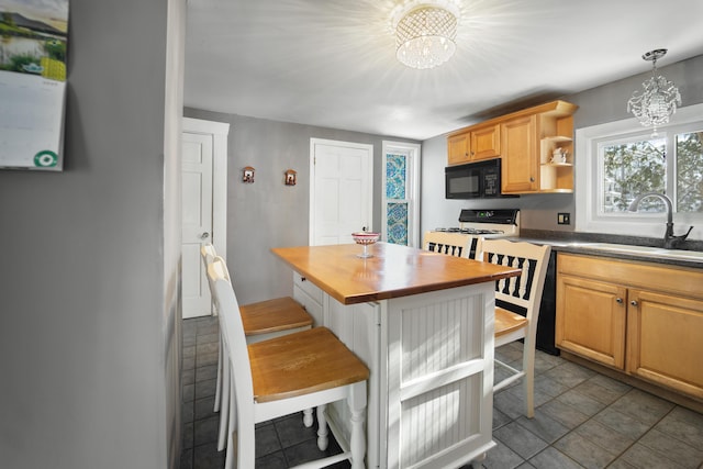 kitchen featuring a chandelier, black microwave, a sink, and gas range gas stove