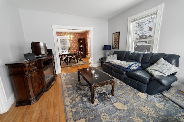 living room with light wood-style floors, a notable chandelier, and baseboards