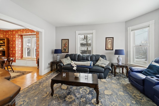 living area with wallpapered walls, baseboards, and wood finished floors