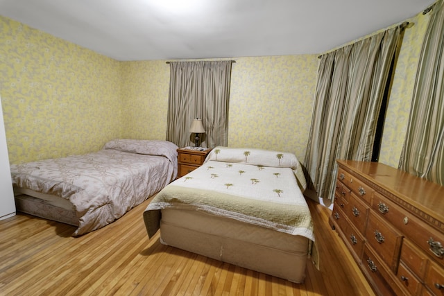 bedroom with hardwood / wood-style floors and wallpapered walls