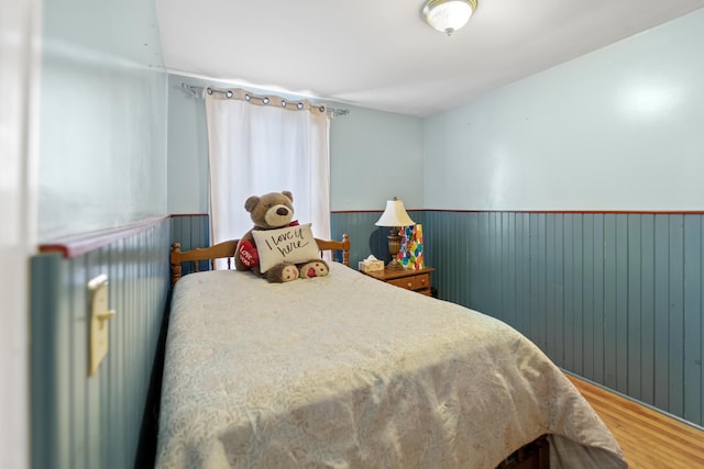 bedroom with wainscoting and wood finished floors