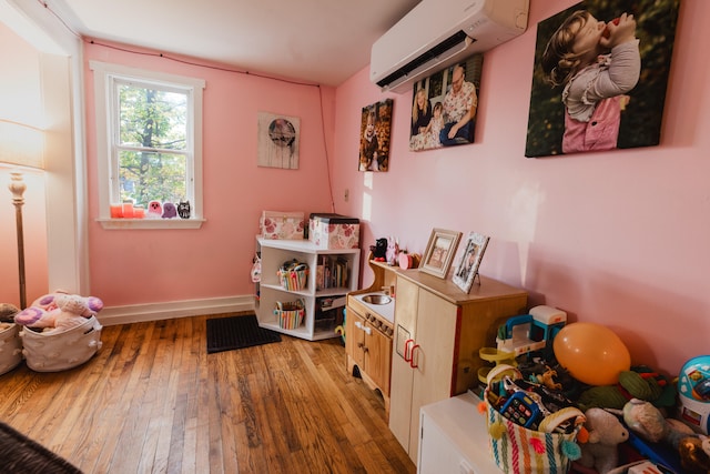 recreation room featuring wood-type flooring and a wall mounted AC