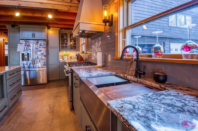 8 Hilltop Hts, Rangeley, ME 04970 - kitchen with stainless steel appliances, premium range hood, rail lighting, glass insert cabinets, and light stone counters