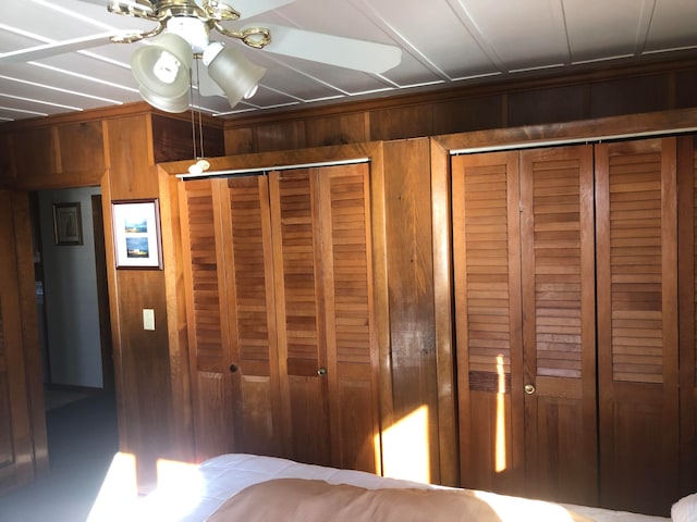 unfurnished bedroom featuring ceiling fan and wood walls