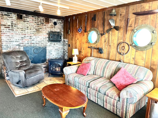 living room featuring wood walls, light colored carpet, a wood stove, and brick wall