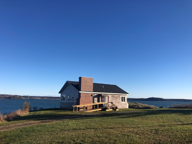 back of property with a lawn and a water view