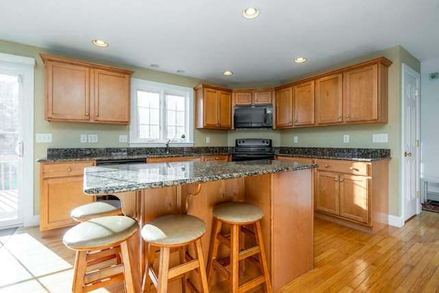 kitchen with a kitchen bar, a kitchen island, and black appliances