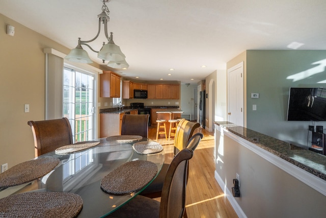 dining room with light hardwood / wood-style floors, an inviting chandelier, and sink