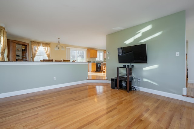 unfurnished living room featuring light wood-type flooring and an inviting chandelier