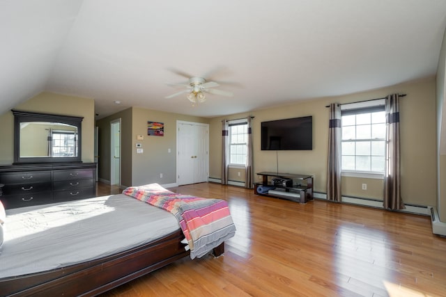 bedroom with light wood-type flooring, baseboard heating, ceiling fan, and lofted ceiling