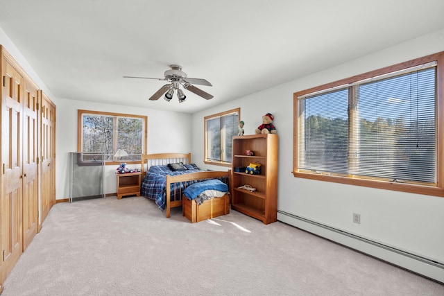 bedroom featuring a closet, light colored carpet, baseboard heating, and ceiling fan