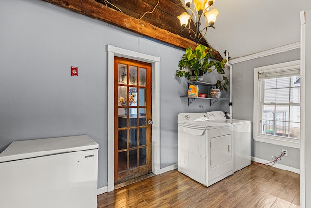 washroom featuring hardwood / wood-style floors, washing machine and clothes dryer, a notable chandelier, and crown molding