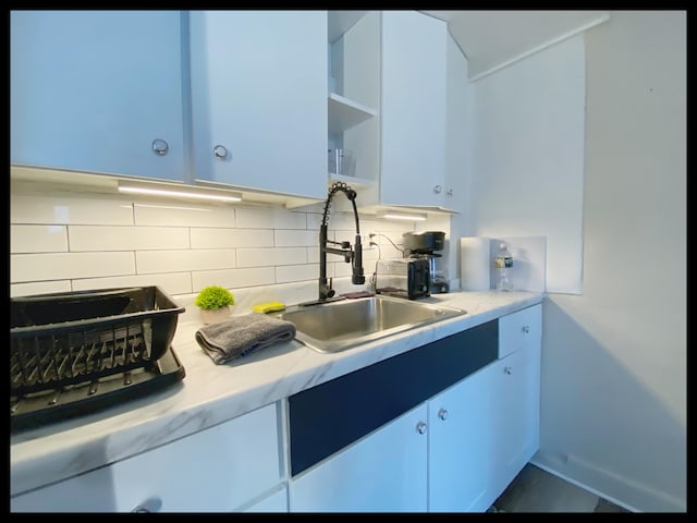 kitchen featuring white cabinetry, sink, and backsplash