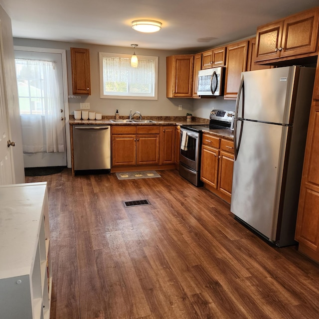 kitchen featuring a healthy amount of sunlight, pendant lighting, stainless steel appliances, and dark hardwood / wood-style floors